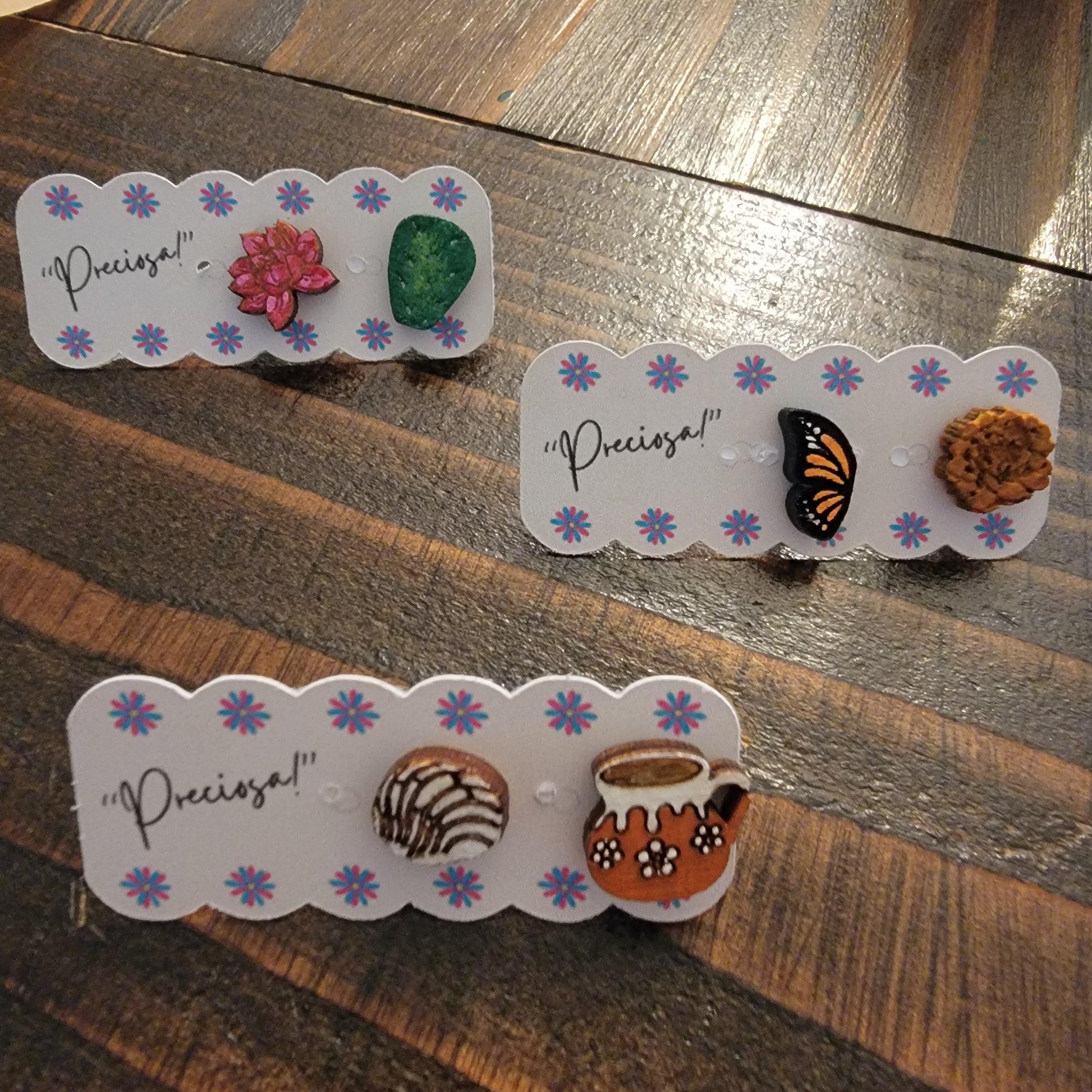 The cutest little studs of monarch butterfly and marigold, saguaro leaf and cactus flower, and barro mug with a pan dulce concha. 